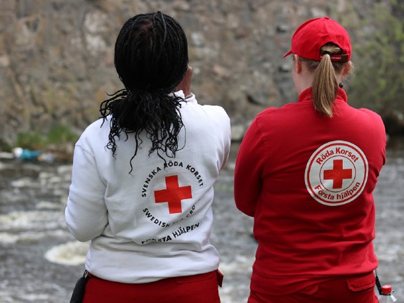 Två kvinnor med Röda Korset tröjor på sig tagit bakifrån