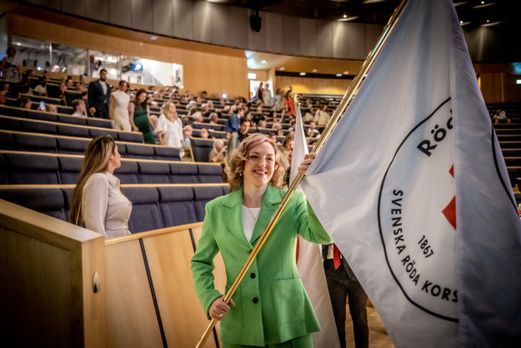 Student som bär flagga med Röda Korsets Högskolas logotyp