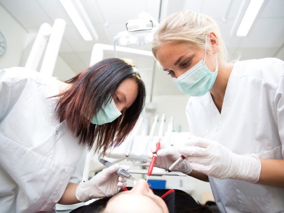 två tandläkare som jobbar med en patient. Foto:Mostphotos