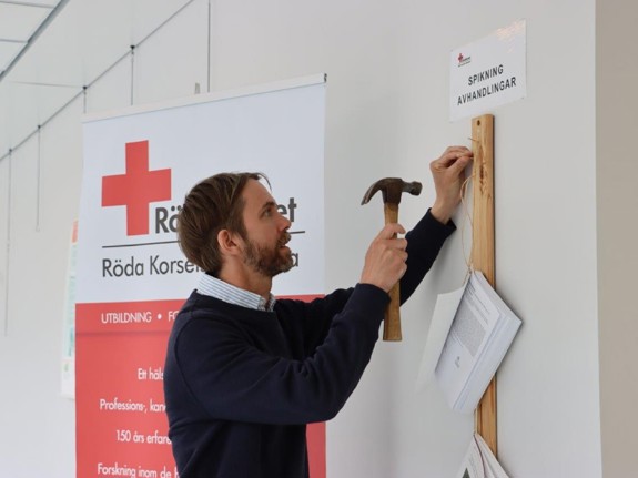 Doktoranden Andreas Malm spikade sin licentiatavhandling på Röda Korsets Högskolas vägg. Foto:RKH