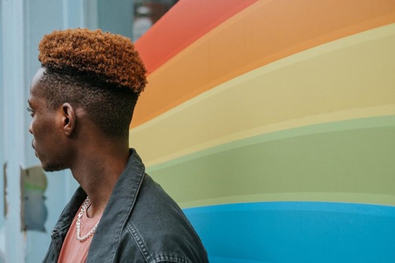 Person som står framför en regnbågsfärgad vägg. Foto: Mostphotos