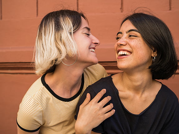 Två kvinnor som håller om varandra och ler. Foto: Mostphotos